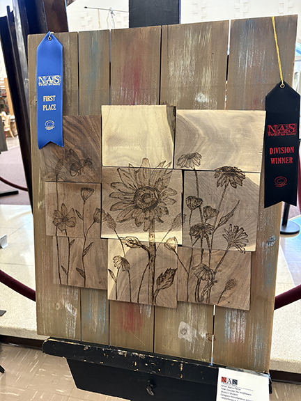 People's Choice winner of a wood burning art piece of several flowers