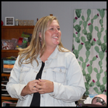 Jamie Niblett smiles while working with students in a Ringwood classroom, wearing a light denim jacket over a black top.